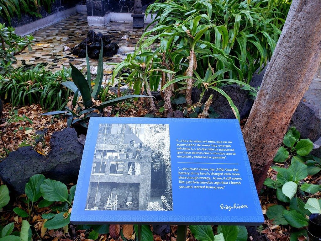 A plaque with a photo of Frida and her husband Diego standing at the stairs that open to the garden view