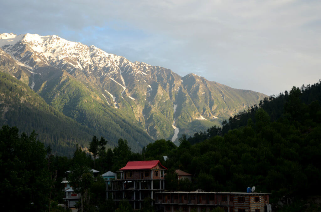 Snow-capped mountains receiving the soft golden rays of the setting sun. Chini village in Kinnaur district.