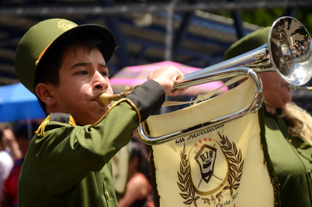 A small boy blowing a trumpet, parade in Heredia to celebrate Independence Day.