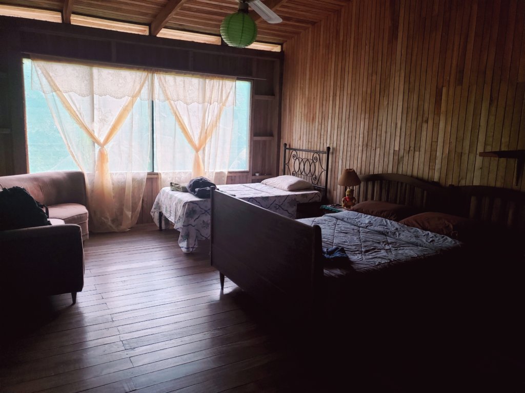 Room at Hostel Casa Sarapiqui - rustic look, wooden floor and wooden walls, 2 beds and a sofa, and large windows