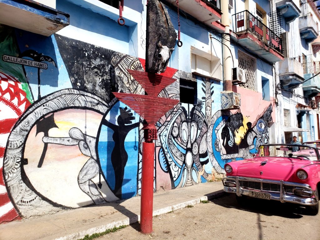 The end of the street named Callejon del Hamel, colorful wall art and pink classic car - signature scenes of Havana