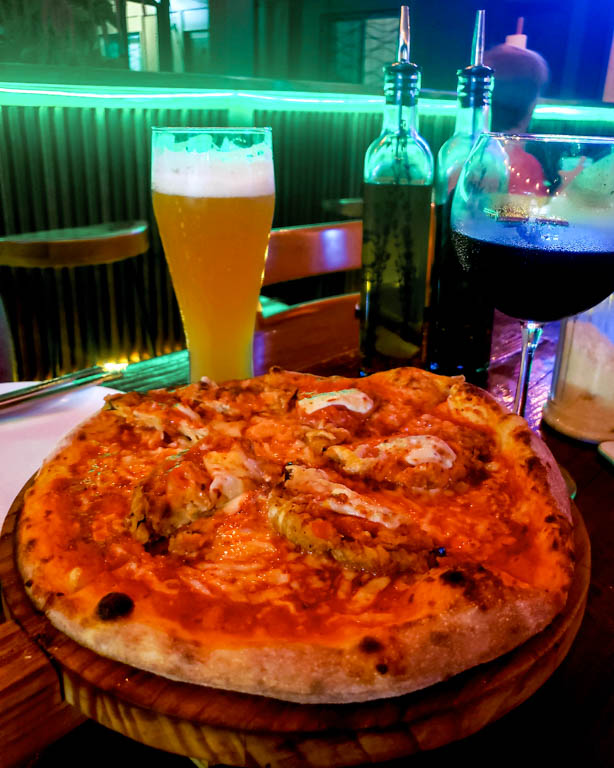 Vegetarian pizza at Pizza Time, Uvita Costa Rica. In frame - an eggplant pizza, a glass of beer and a glass of red wine.