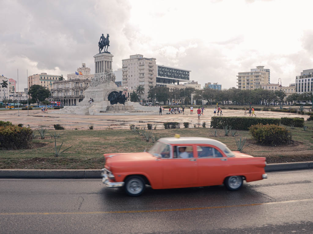 A typical sight in Havana, Cuba - an orange colored vintage car on the road.