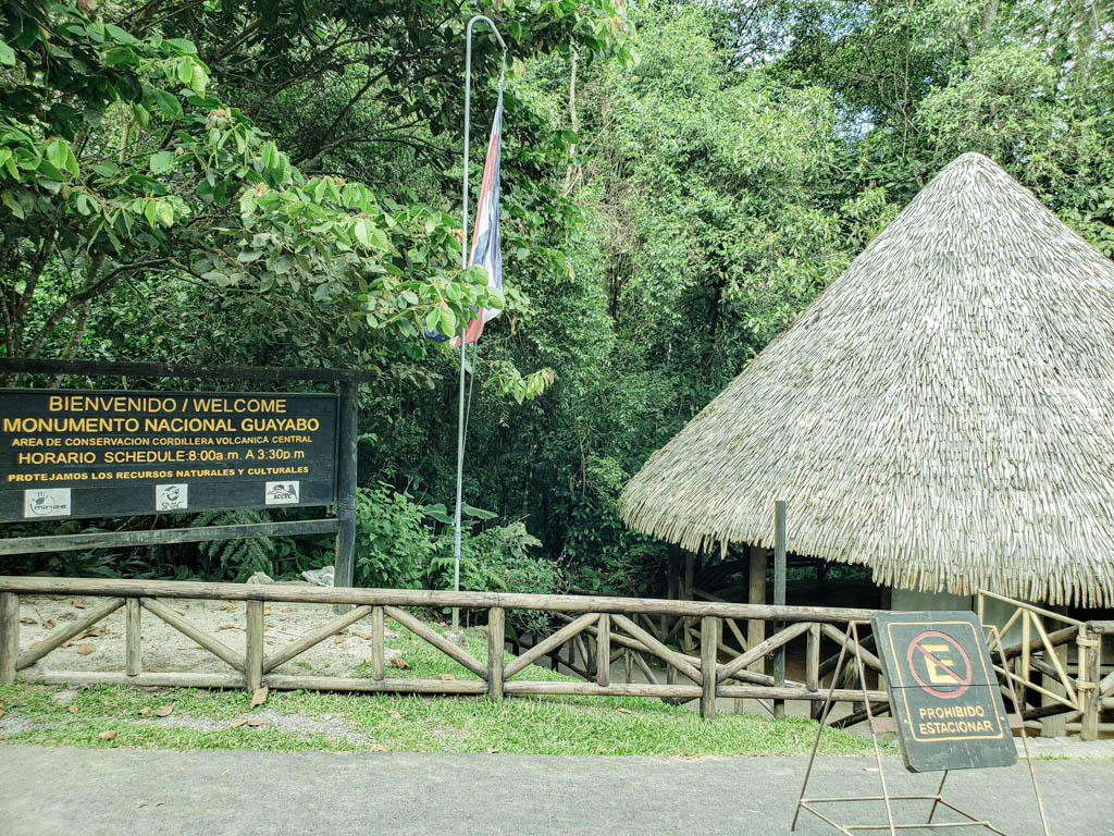Entrance to Guayabo National Monument. A black welcome board with yellow text stating the name of the venue and the schedule.