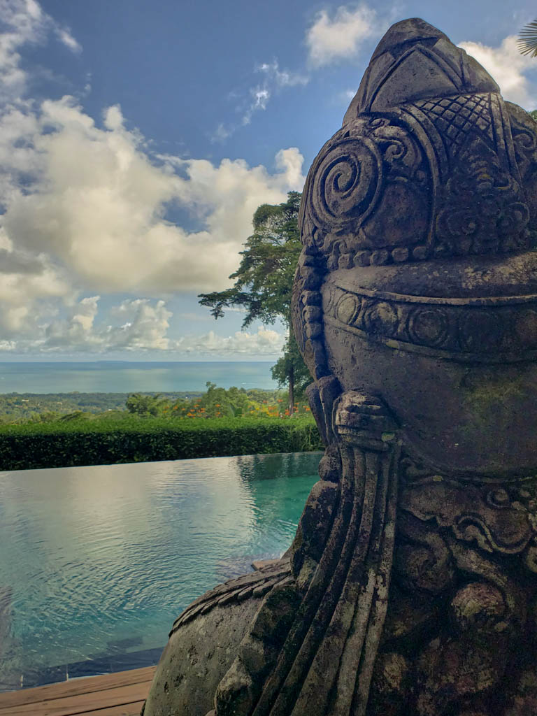 A stone statue next to a pool with Pacific ocean views in Oxygen Jungle Villas, one of the amazing Eco lodges in Costa Rica