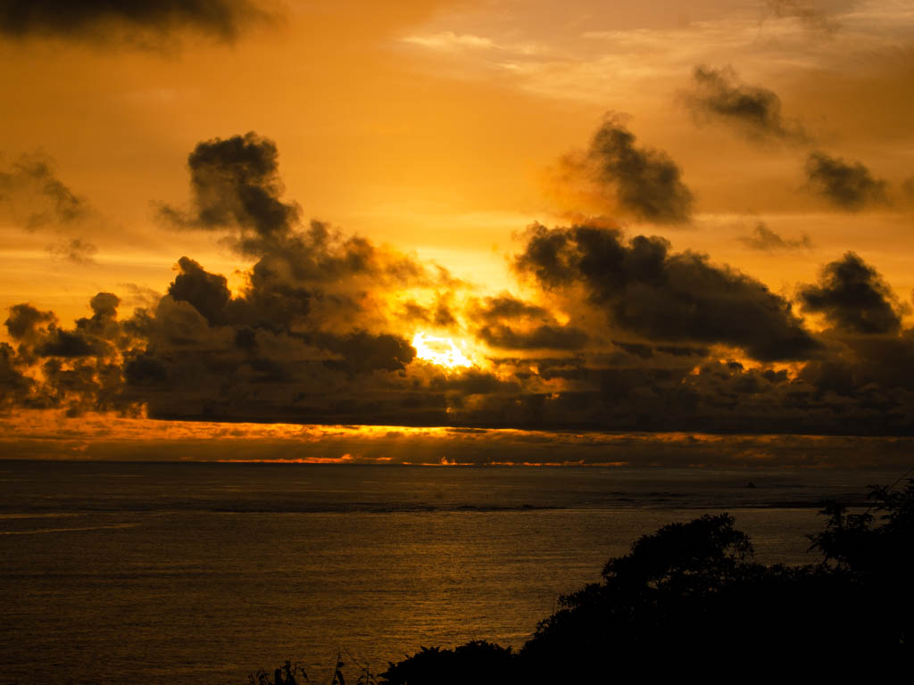 Sunset from Aracari Restaurant - golden sky as the sun rays and clouds create a dramatic view over the Pacific Ocean.