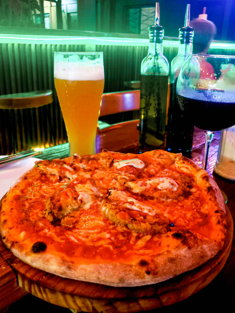 Eggplant Pizza, a glass of beer,, a glass of wine at Pizza Time restaurant in Uvita.