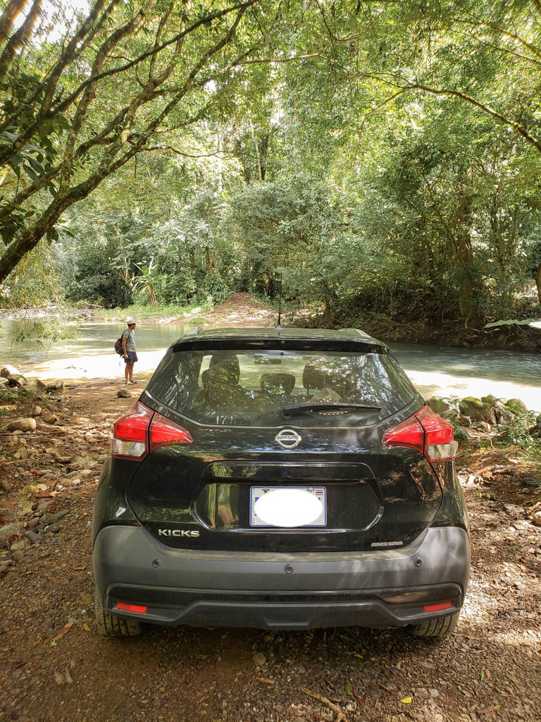 A black car parked next to the river.