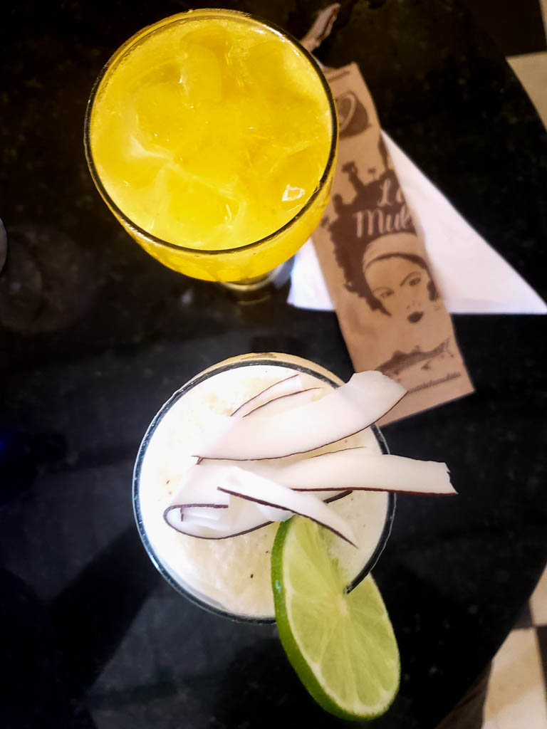 Top view of two tall glasses with chilled beverages, one passion fruit and the other coconut.