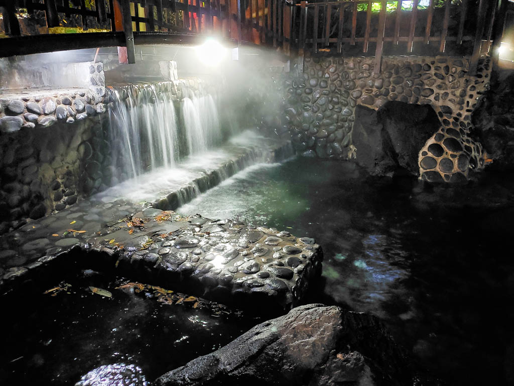 Waterfall of Volcanic Hot Springs falling into the pool at night