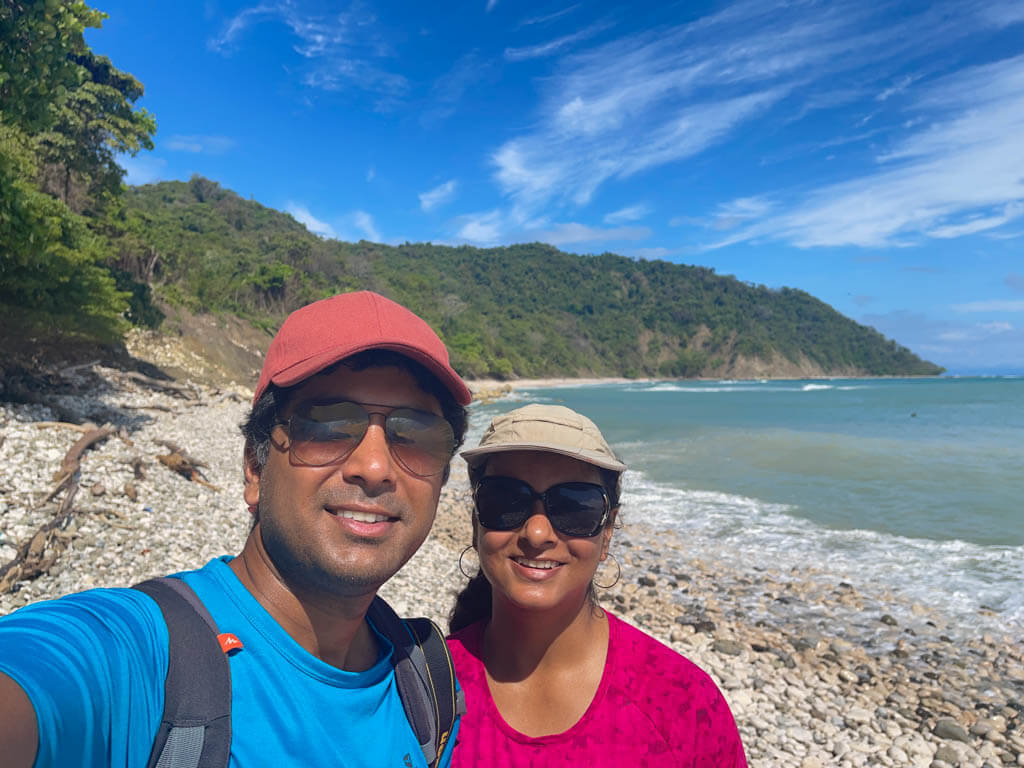 A man and woman smiling at the camera, on the Cabo Blanco Beach. The hidden beach in the Cabo Blanco Absolute Natural Reserve.