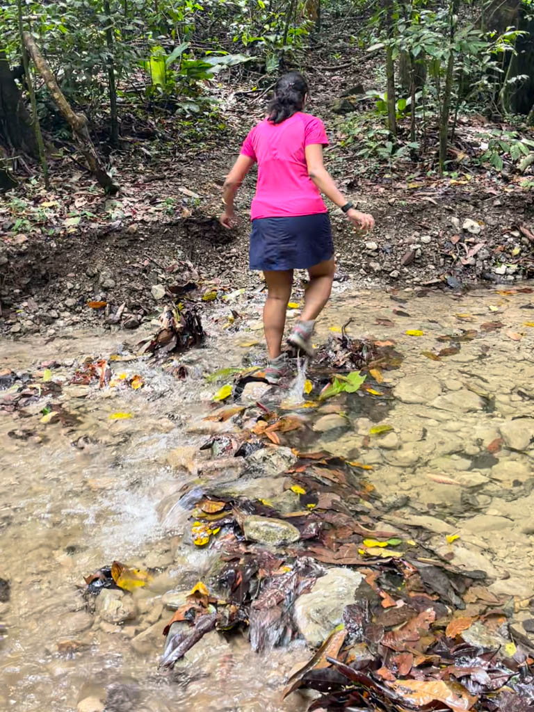 A woman crossing a stream on the Sueco Trail.