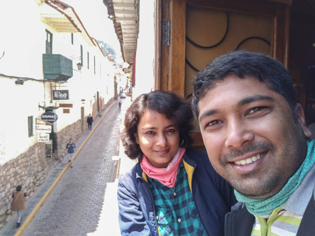 Paradise Catchers, smiling by the window with a view of cobblestone street in Cusco, Peru.