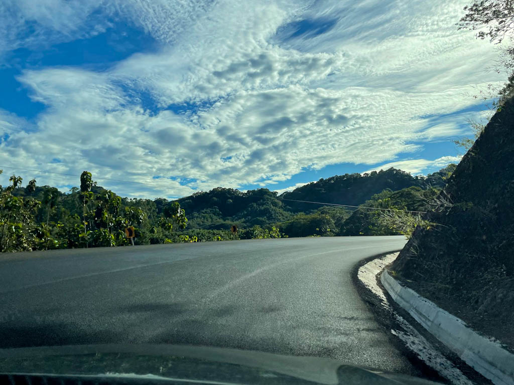 Paved unmarked road after Paquera. Blue sky with white clouds.