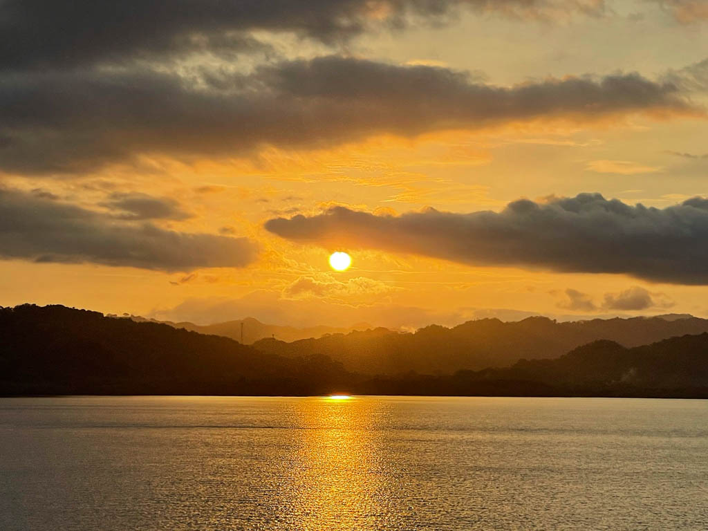 The setting sun, sunset hour golden sky, rolling expanses on green islands and the glistening ocean water - all in the frame, creating an awesome sunset view while returning by ferry from Paquera to Puntarenas.