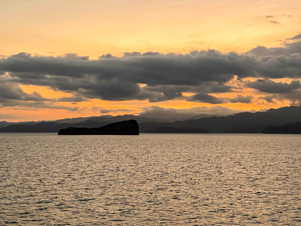 View from the Puntarenas Ferry - several islands on the Gulf of Nicoya. The sky is painted orange due to sunset hour colors.