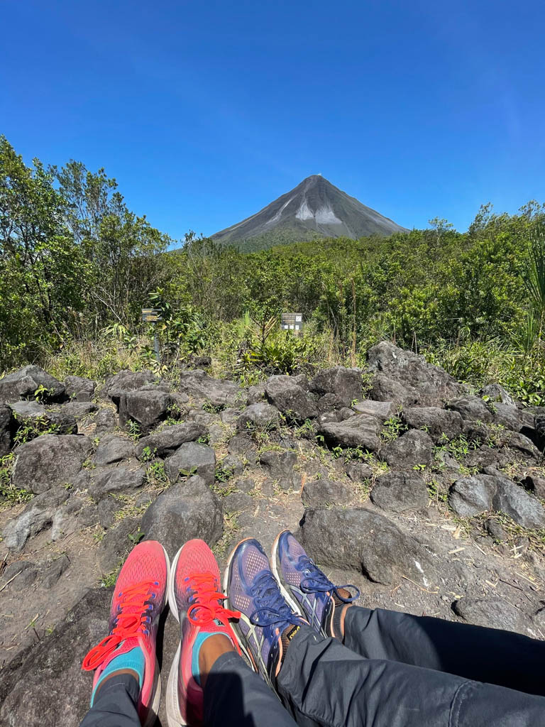 Arenal Volcano view from the Las Coladas trail of National Park and feet of a man and woman.