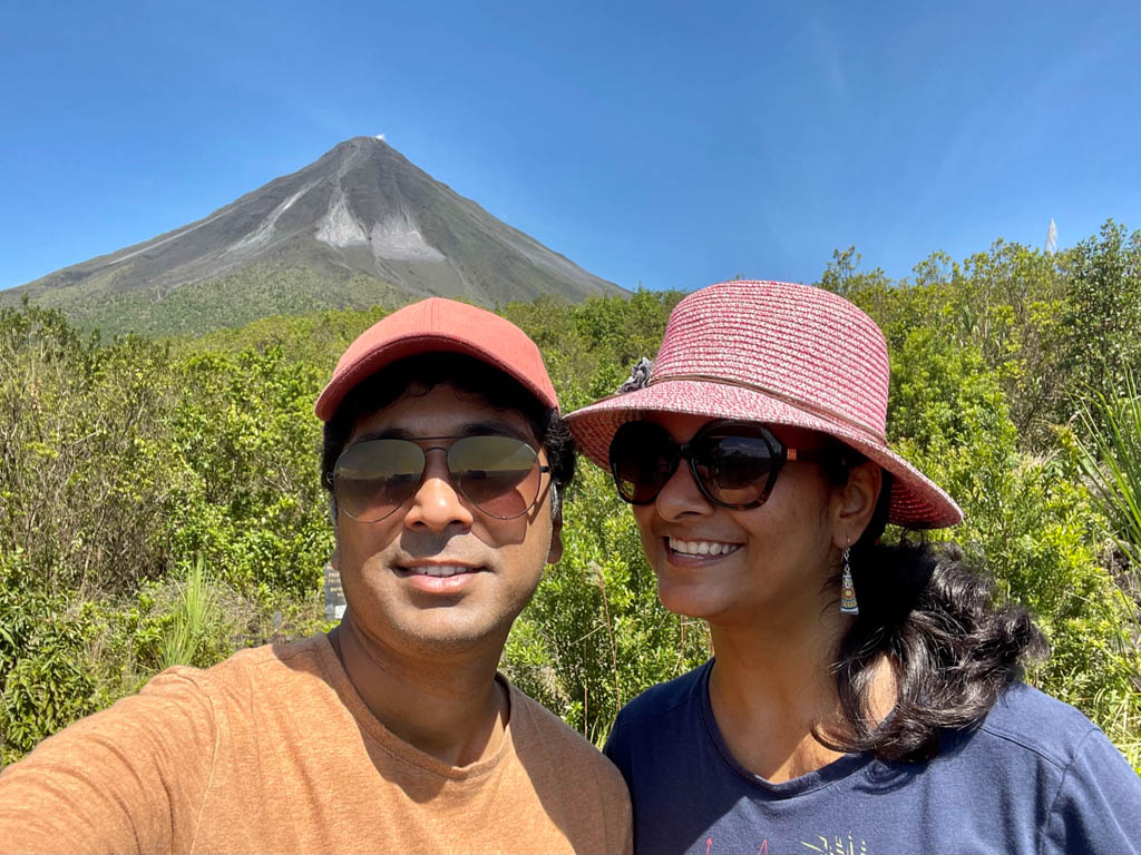 Man and woman standing on the Las Coladas trail with Arenal Volcano in the background.