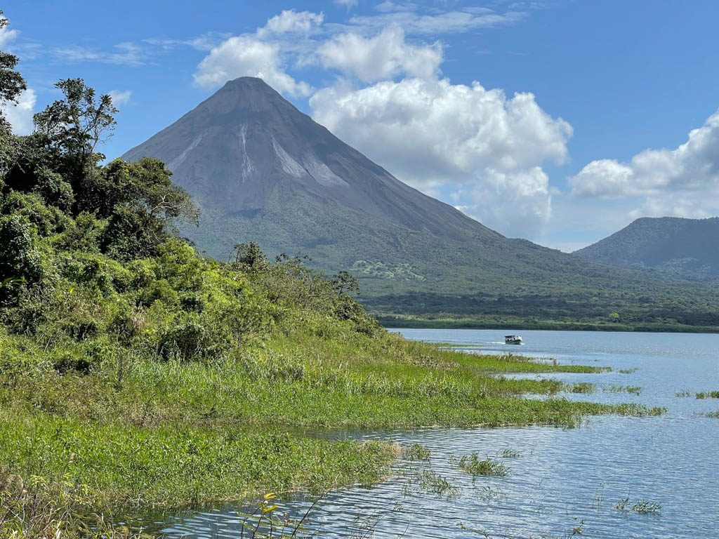 Arenal Volcano and Arenal Lake on a clear day with blue sky. Seen from the third Mirador at Peninsula Sector of Arenal Volcano National Park.