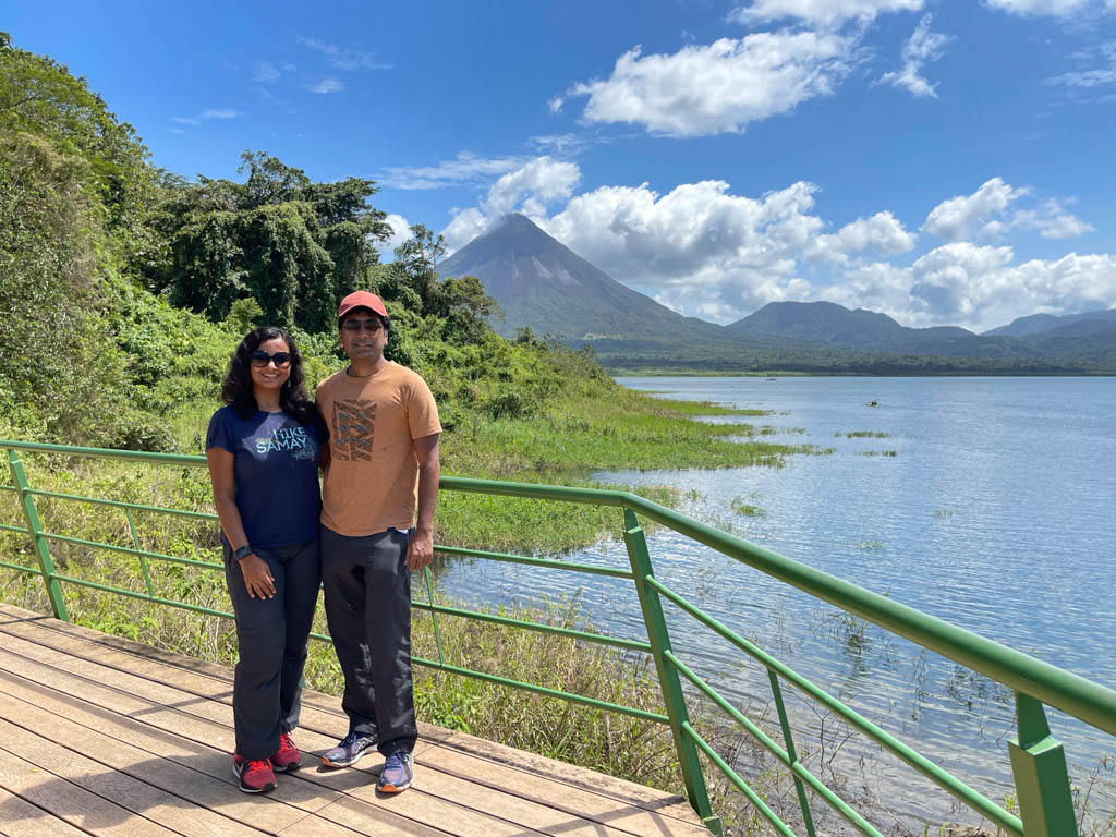 Man and Woman sitting on the final viewpoint deck of the Peninsula sector. Arenal Volcano and Arenal Lake are seen in the background.