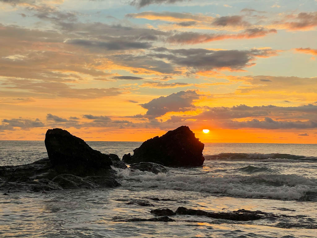 Sunset at Malpais, Costa Rica. Two rocks in the ocean forming the foreground of an orange sky during sunset.
