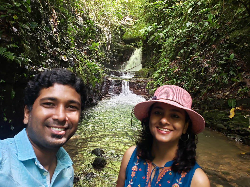 Paradise Catchers in Uvita. A waterfall in the jungle forming the background of this couple, the man wearing a blue shirt and the woman 