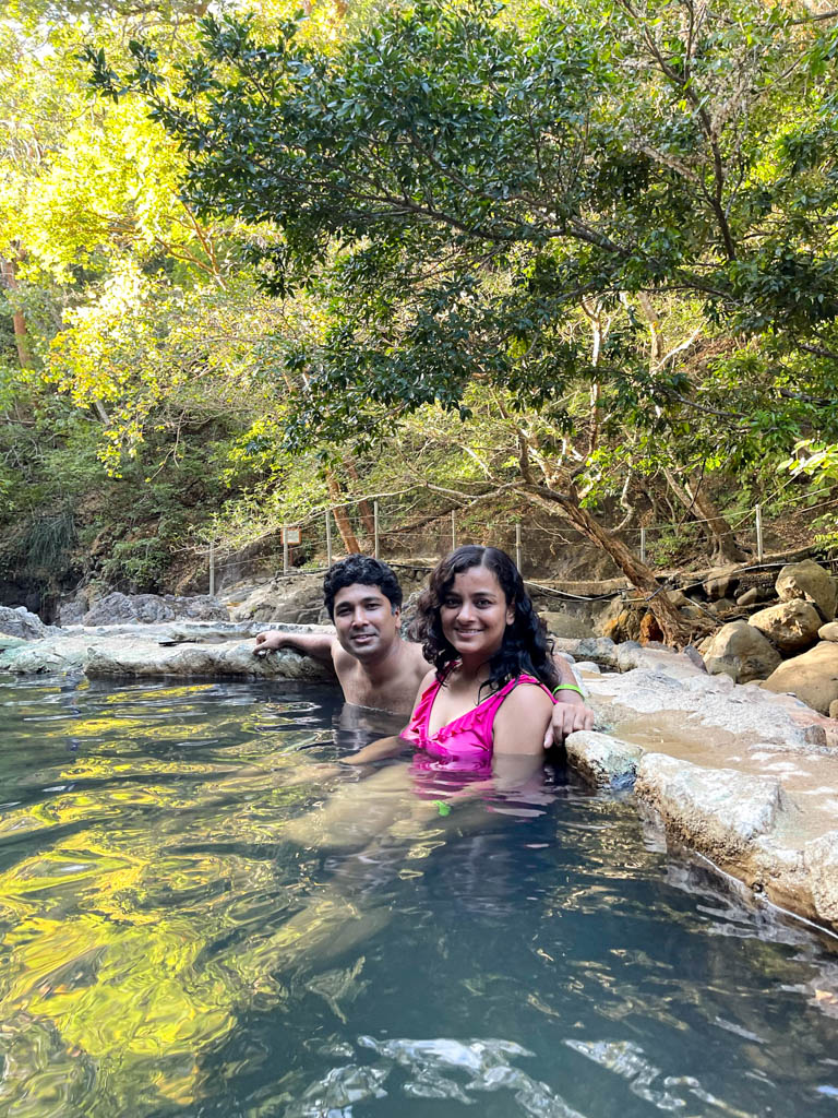 Man and woman relaxing in a thermal pool surrounded by tropical dry forest of Guanacaste.
