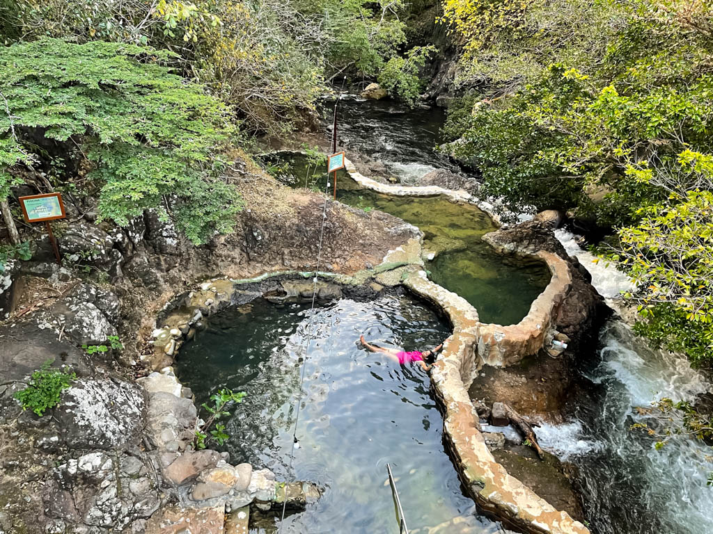 Woman wearing pink swimsuit relaxing at the thermal pool of Rio Negro Hot Springs.