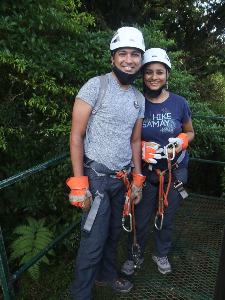 A man and woman with zip lining gears on a platform.