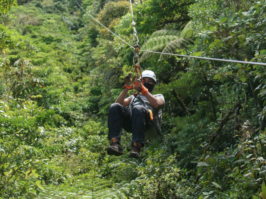 A man zip lining in the middle of the trees. 