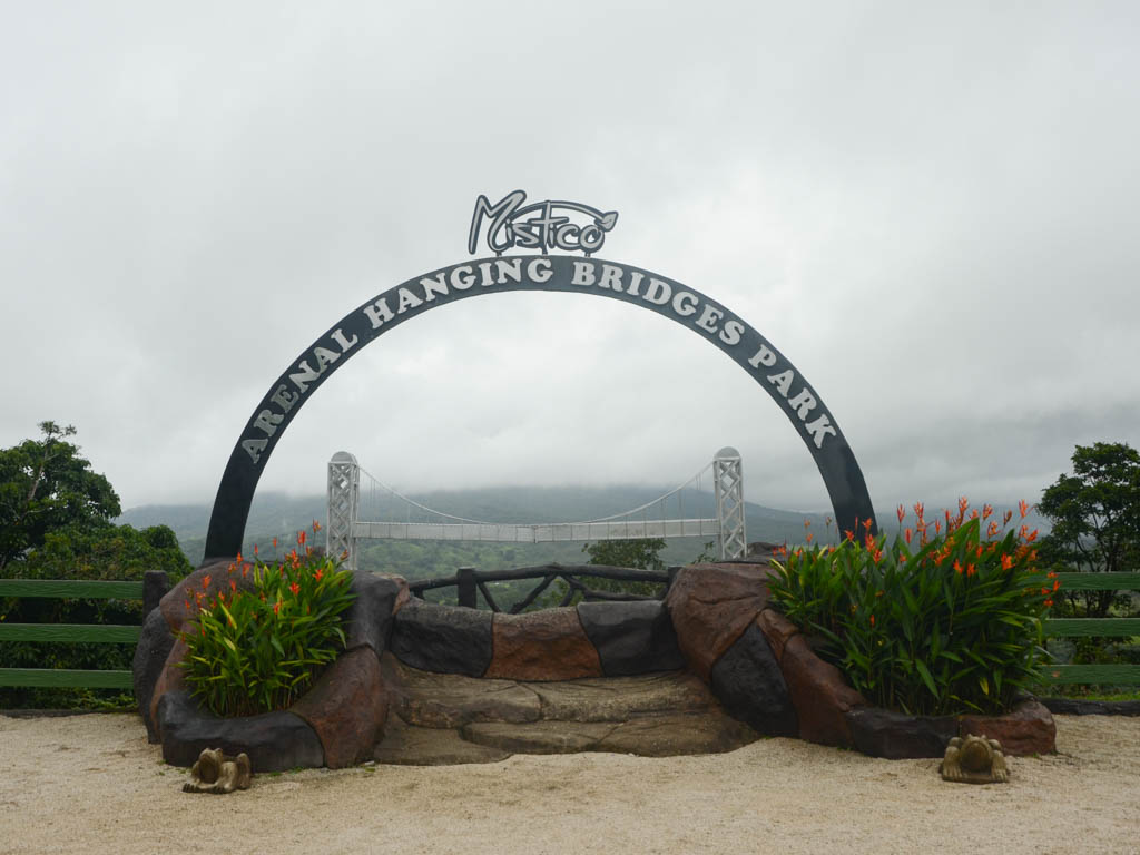 The Mistico Arenal Hanging Bridges Park arch near the entrance. The Arenal Volcano hidden behind the clouds in the background.