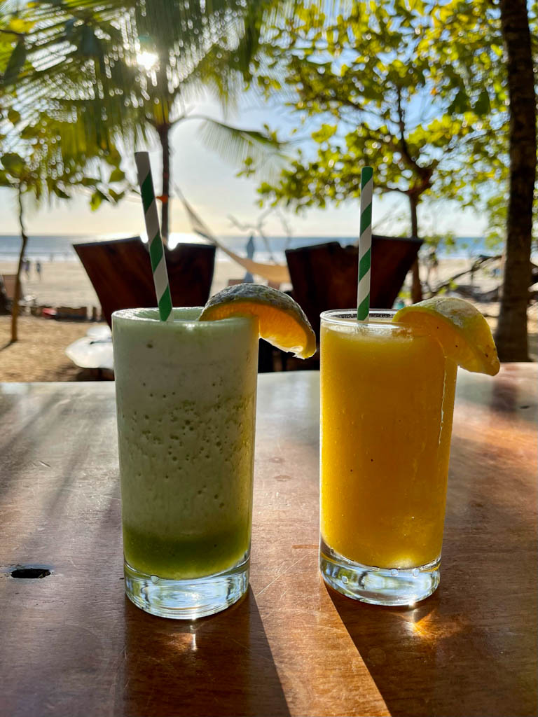 Two glasses of tropical cocktails at Lola's restaurant. Sunset sky in the background.
