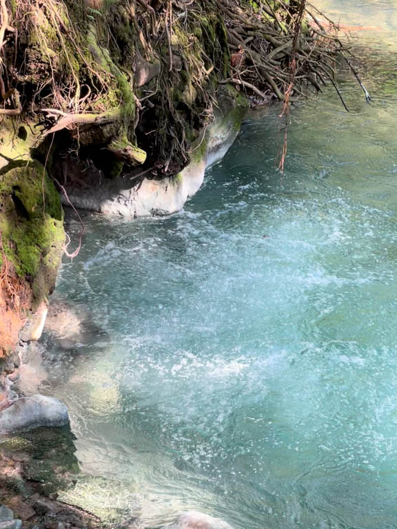 The bubbling hot water in the river, a geothermal activity.