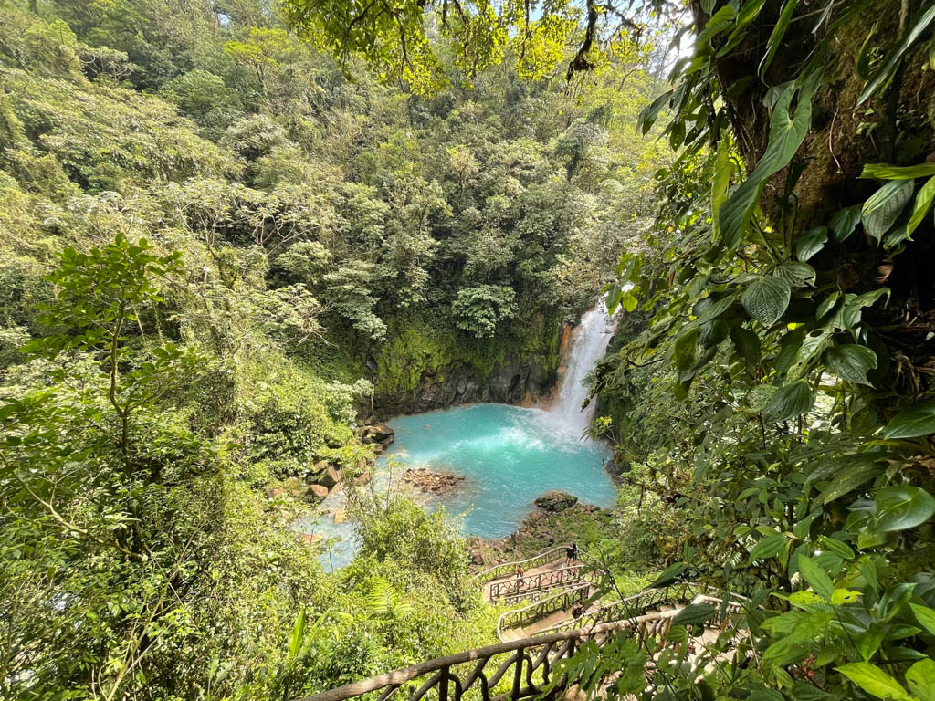 The spiraling wooden staircase to the Rio Celeste waterfall surrounded by lush green rain forest.