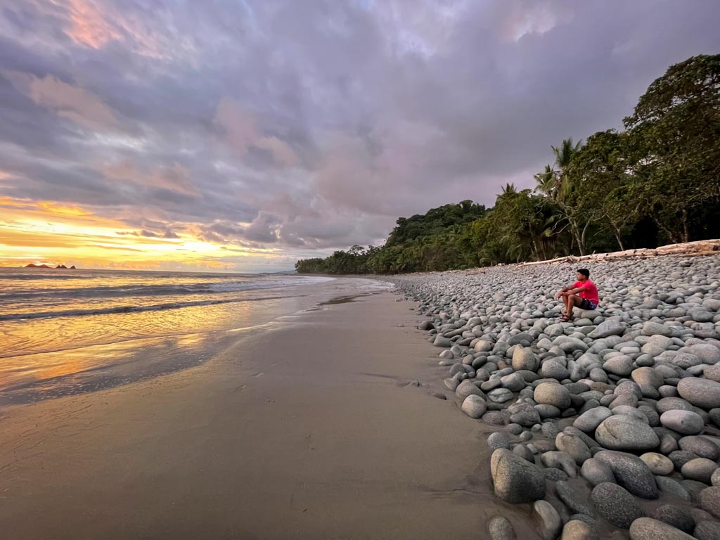A man sitting on the beach rocks.