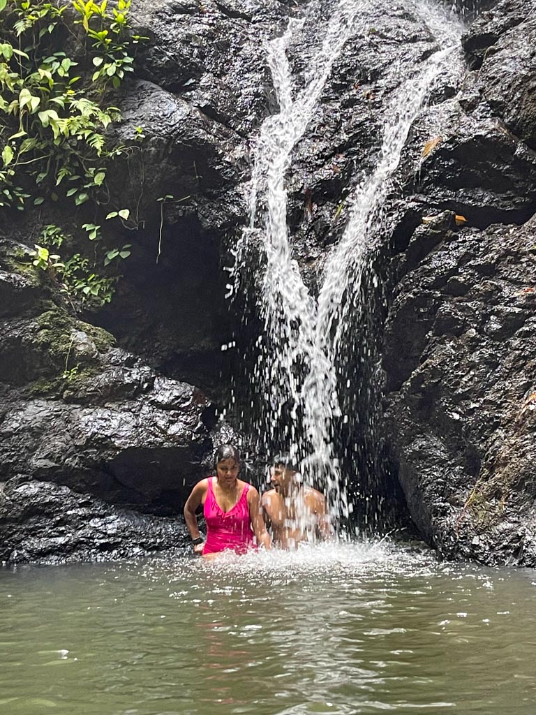 A man and a woman below the Rio Claro Waterfall.