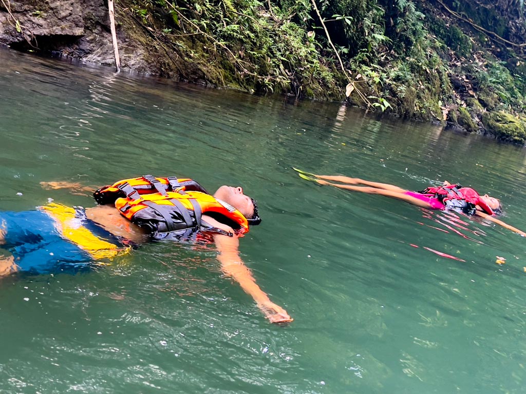 A man and a woman floating in Rio Claro, a river adventure activity.