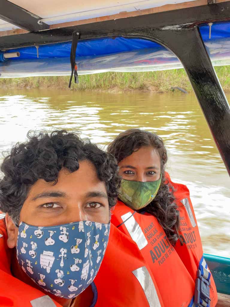 Selfie of a man and a woman, wearing life jackets and face masks, sitting in the boat for going to Tortuguero.
