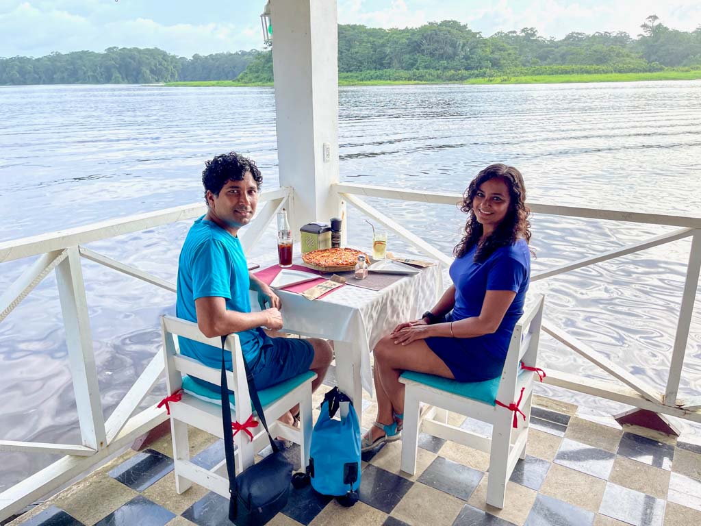 Couple wearing color coordinated blue sporty clothes dining at a riverside cafe, belonging to Budda Home, a nice place to stay in Tortuguero.