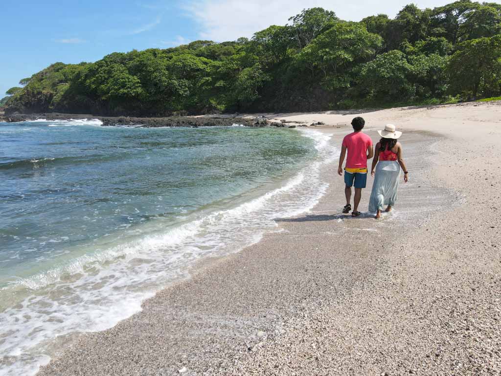 A man and a woman walking on the beach at Playa San Juanillo in Costa Rica.