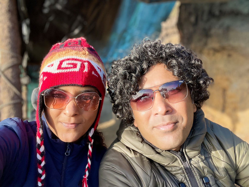 Selfie of a couple, man and woman both wearing sunglasses for the sun, jackets for the cold.
