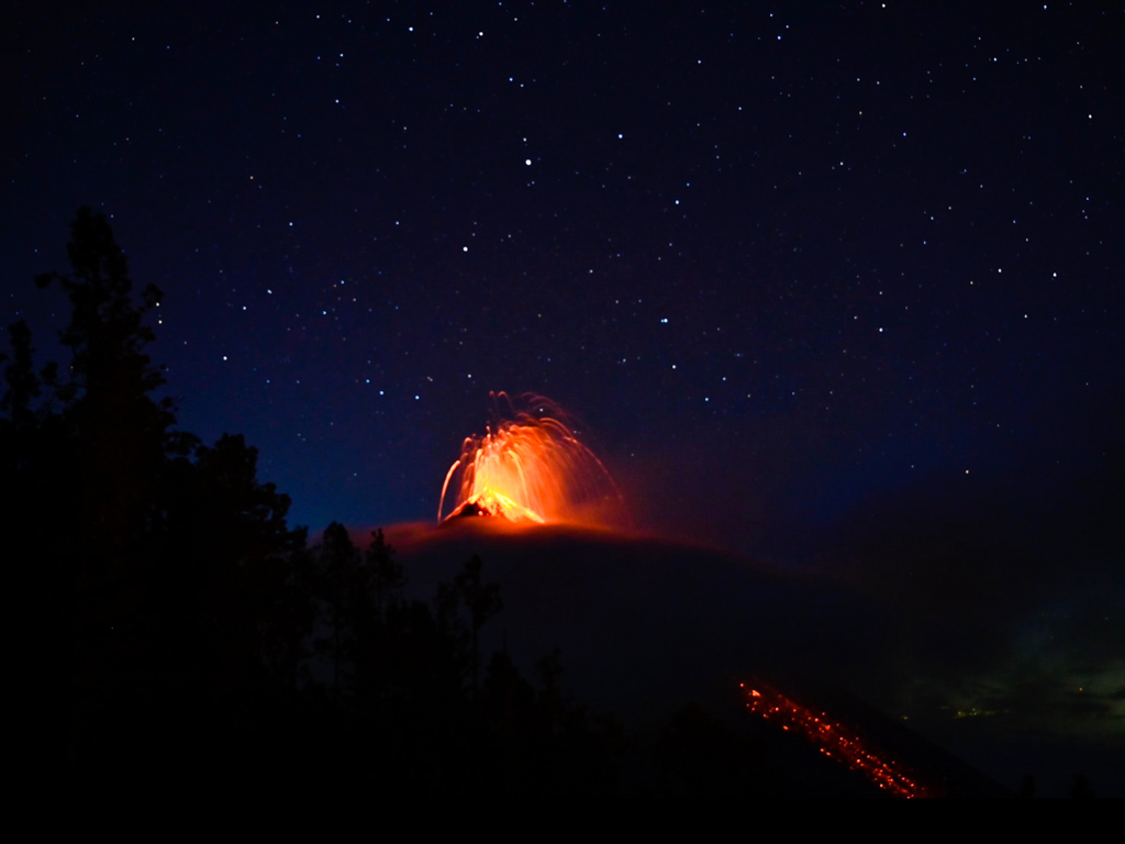 Long exposure shot of erupting Fuego volcano on a starry night, as seen from Acatenango base camp.