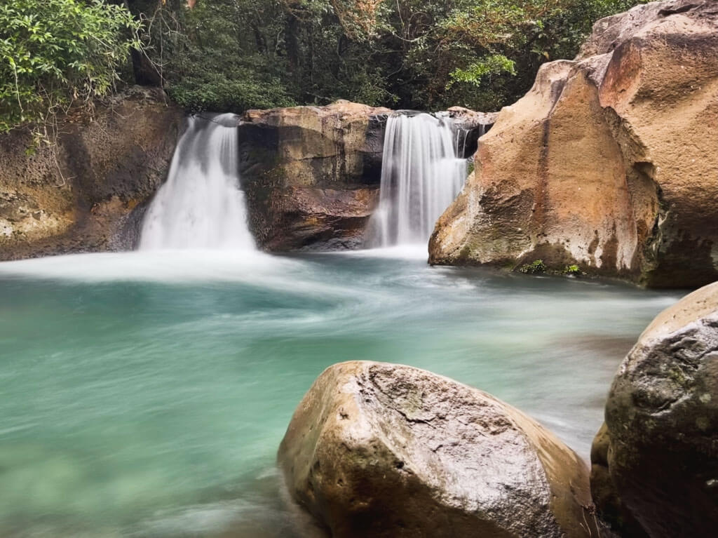 Las Chorreras Waterfalls, surrounded by rocks, and pouring into a green pool.