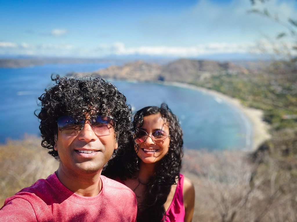 Selfie of a couple with curly hair, with the Hemosa Bay in the backdrop.