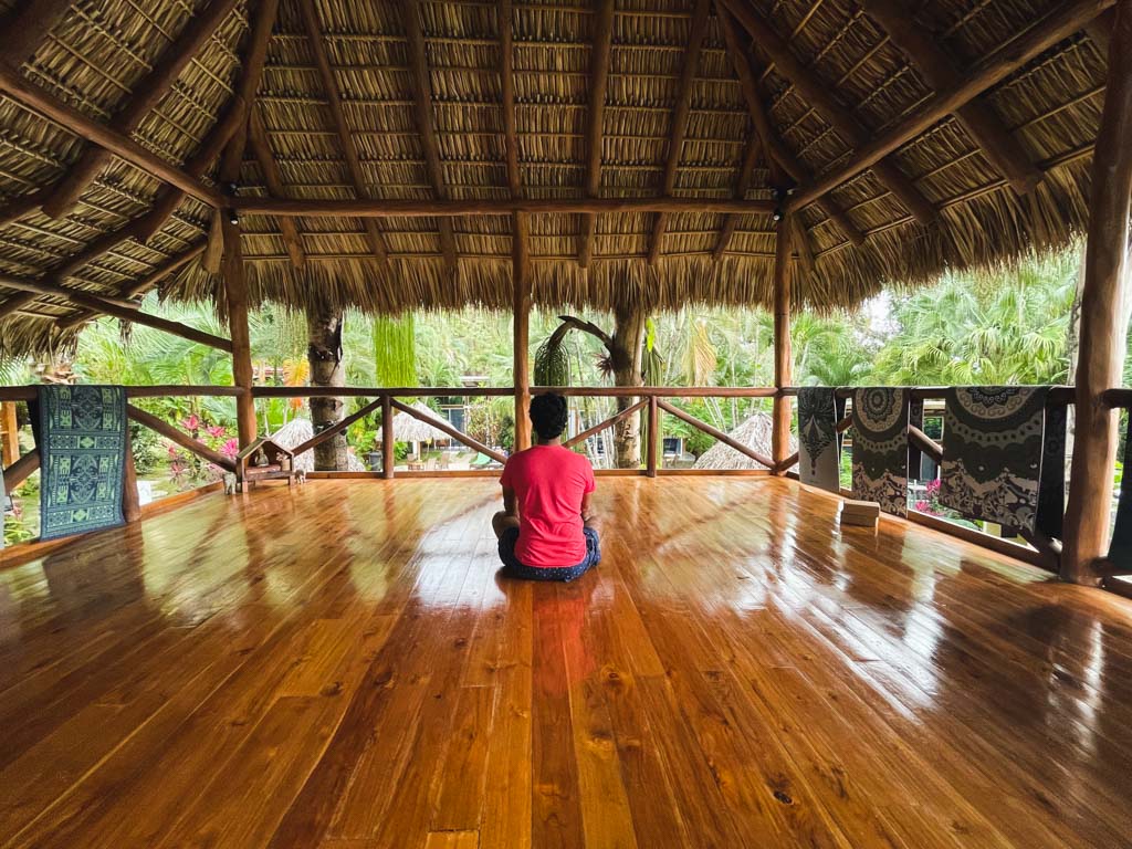 A man in red t-shirt doing yoga on the yoga floor of a lodge in Santa Teresa, Costa Rica.
