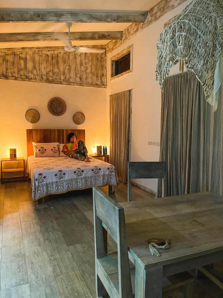 A man, relaxing in the cozy room with neutral color tones and mood lighting at Sonora Jungle Retreat in Playa Negra.
