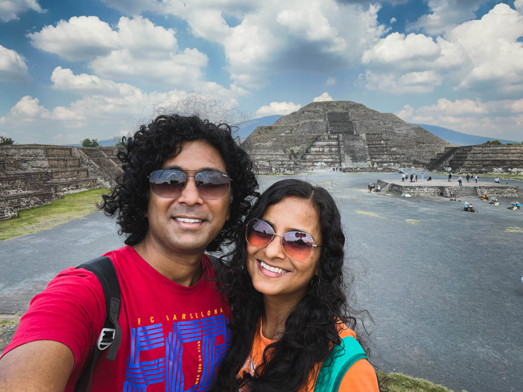 A couple taking a selfie with the Pyramid of the Moon in the background, when visiting Teotihuacan in Mexico.
