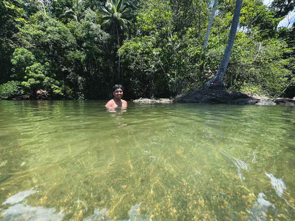 A man swimming in a river surrounded by the lush tropical jungle of Costa Rica.