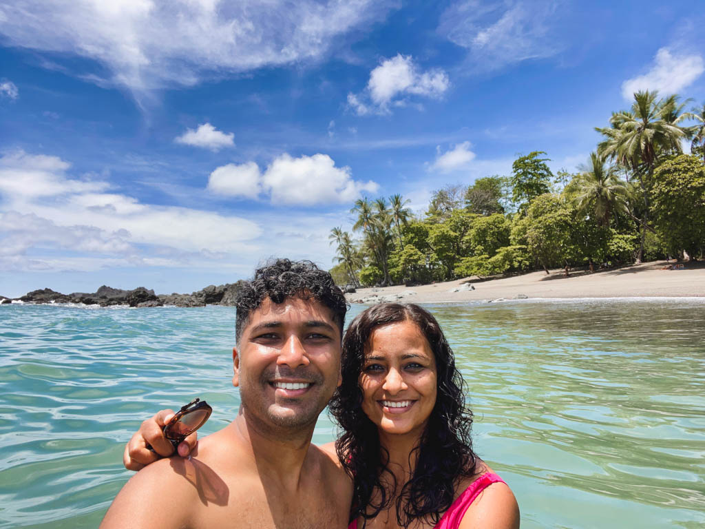 A couple posing for a selfie, while swimming in the Pacific Ocean surrounded by lush tropical forest of the Osa Peninsula region in Costa Rica.