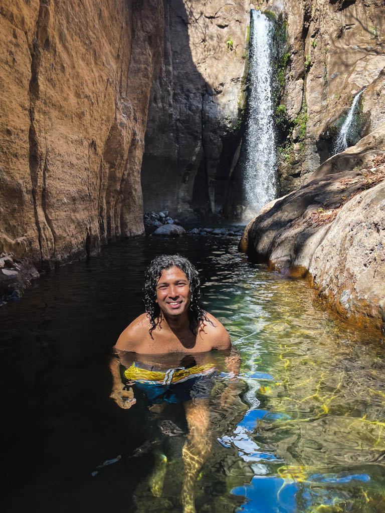 Man with curly hair, enjoying his swim at Tamanique waterfalls in El Salvador.